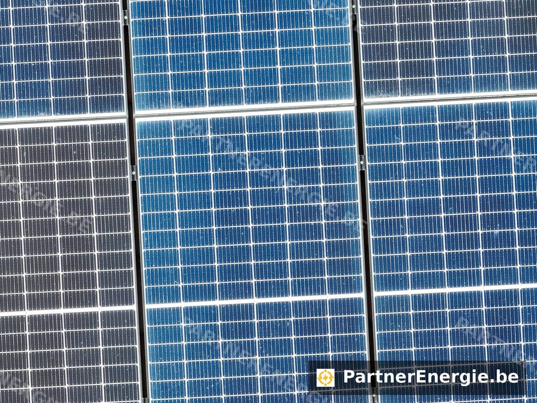 Vue thermique aérienne d'une toiture avec panneaux photovoltaïques sur deux versants, points chauds visibles