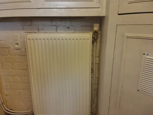 Technicien à l'écoute d'un tuyau de chauffage pour repérer l'origine d'un bruit de radiateur