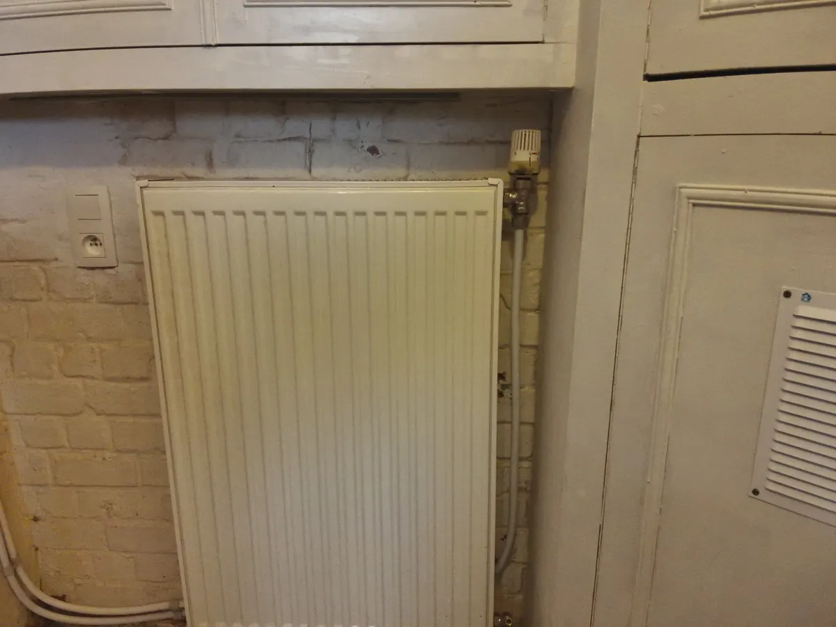 Technicien à l'écoute d'un tuyau de chauffage pour repérer l'origine d'un bruit de radiateur