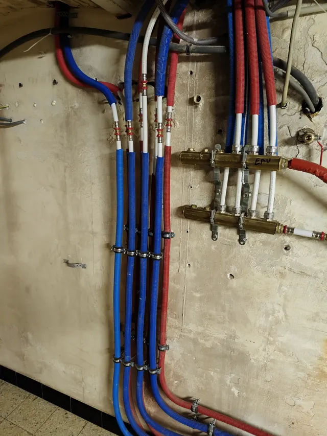 Technicien raccordant un équipement de désembouage sur un circuit de chauffage central