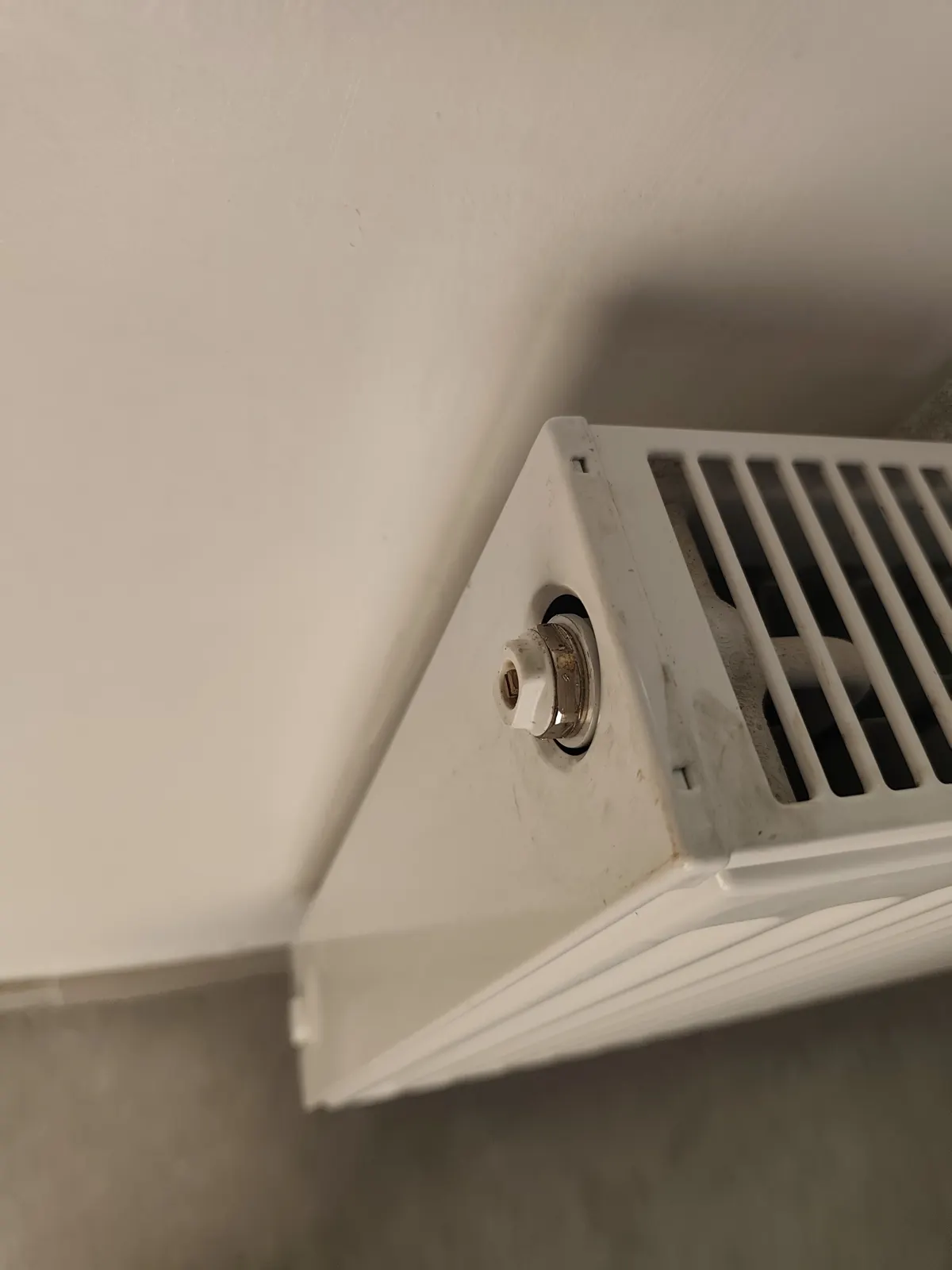 Technicien surveillant le rinçage d'un circuit de chauffage devant une chaudière murale