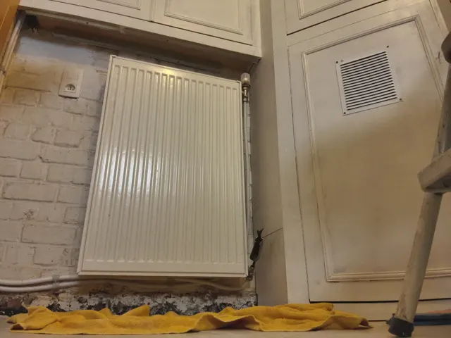 Radiateur dans une maison en octobre avec main vérifiant la chaleur avant l'hiver