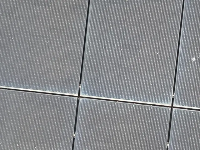 Technicien nettoyant des panneaux solaires sur une toiture de maison dans la région de Mons