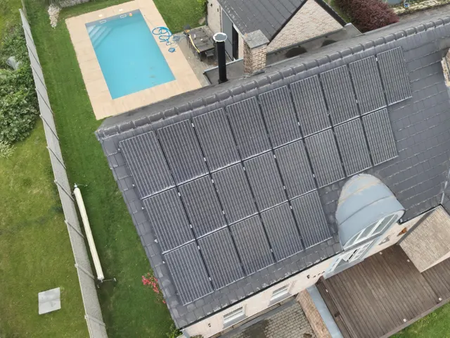 Technicien discutant d'un devis avec un propriétaire devant sa maison équipée de panneaux solaires