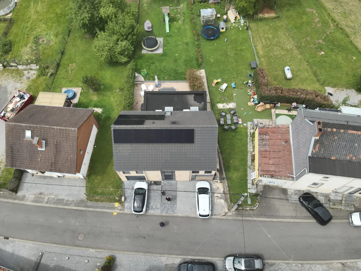 Technicien nettoyant des panneaux solaires sur une toiture de maison en Brabant wallon
