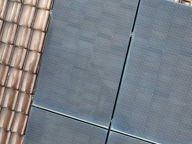 Propriétaire consultant ses documents d'installation photovoltaïque devant un onduleur mural