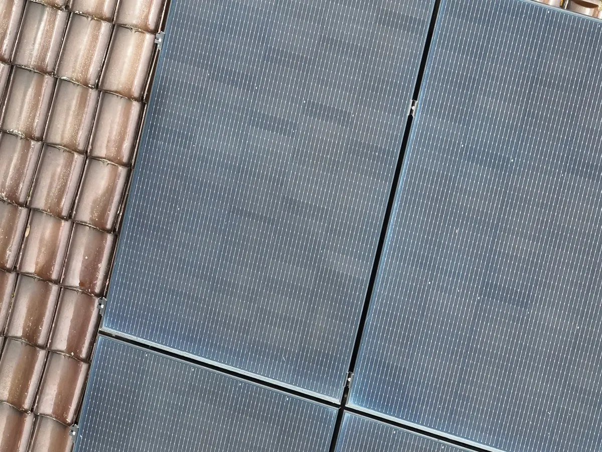 Propriétaire consultant ses documents d'installation photovoltaïque devant un onduleur mural