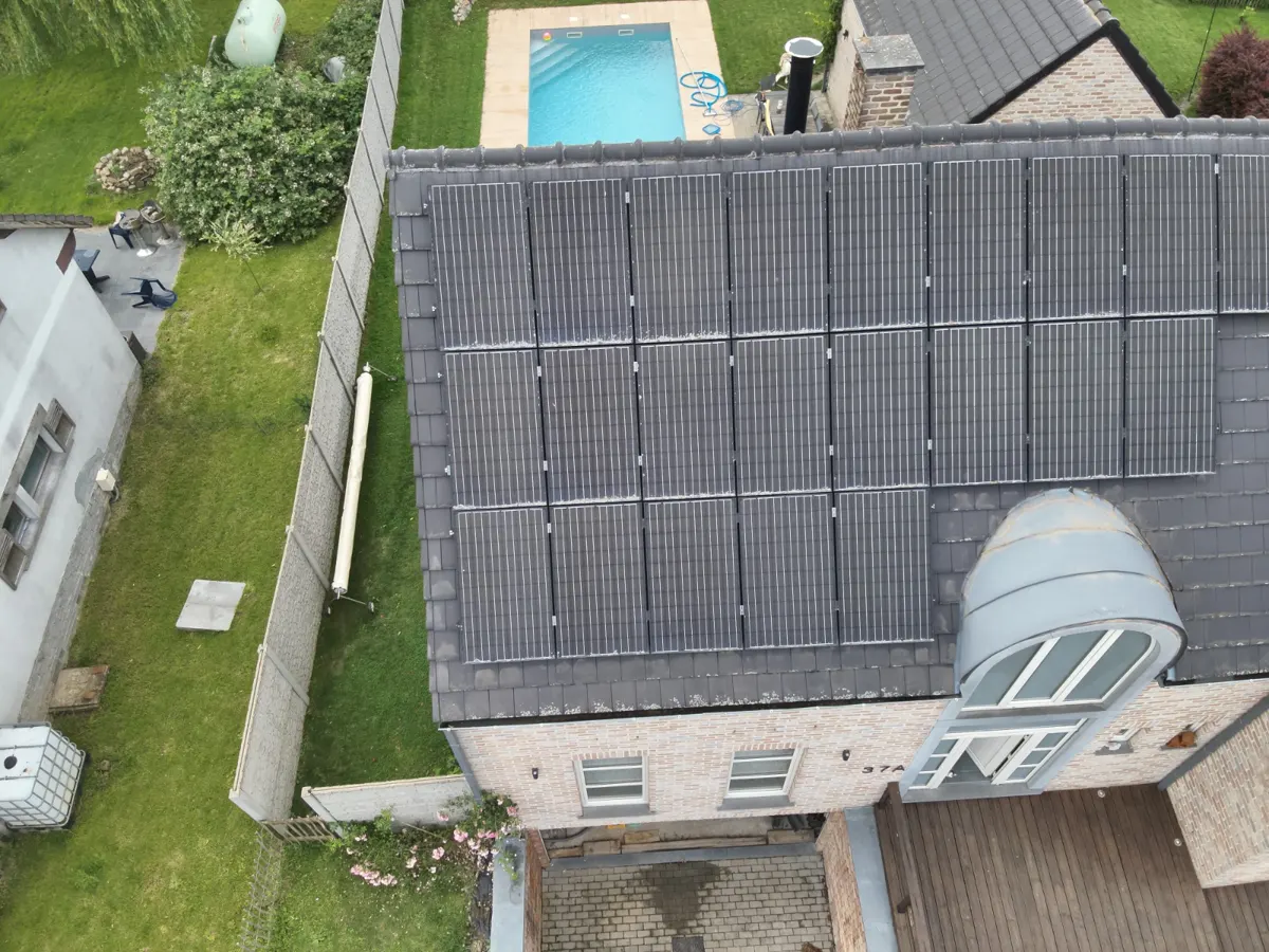 Télépilote préparant un drone thermique devant une maison équipée de panneaux solaires