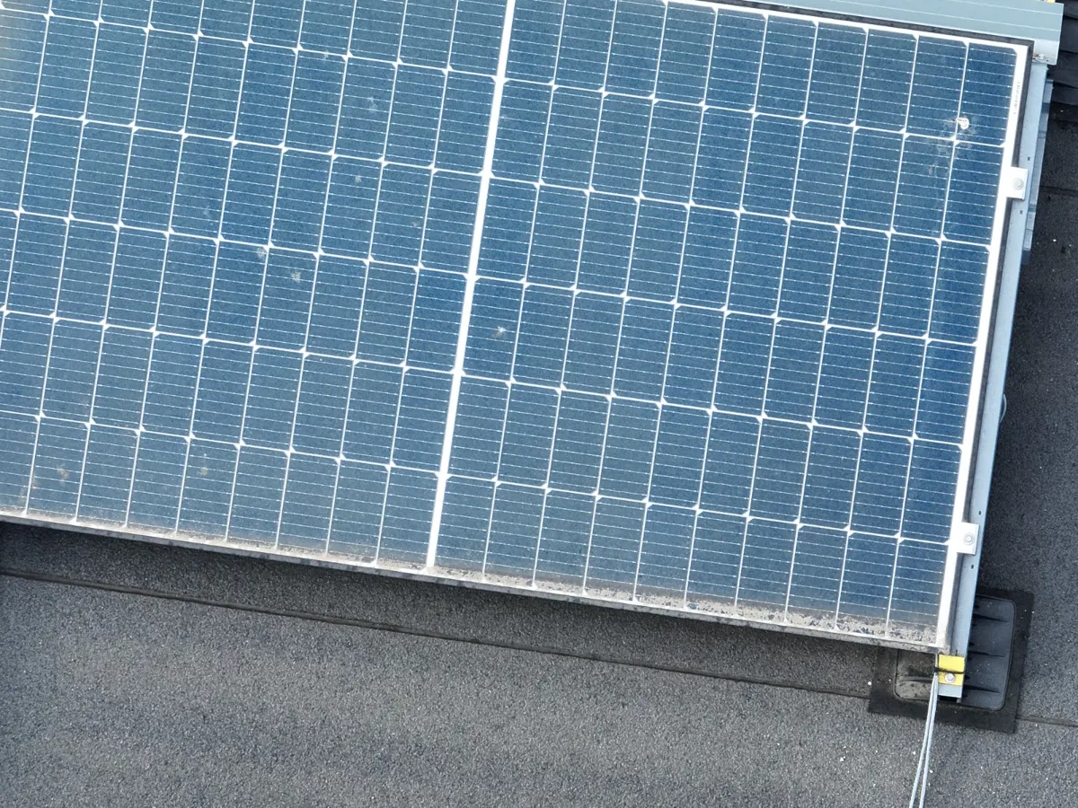 Rangées de panneaux solaires faiblement inclinés sur un toit plat avec dépôts de saleté en bas